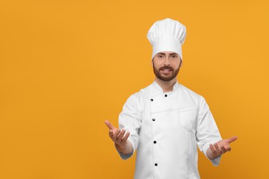 Photo of Smiling mature chef on orange background, space for text