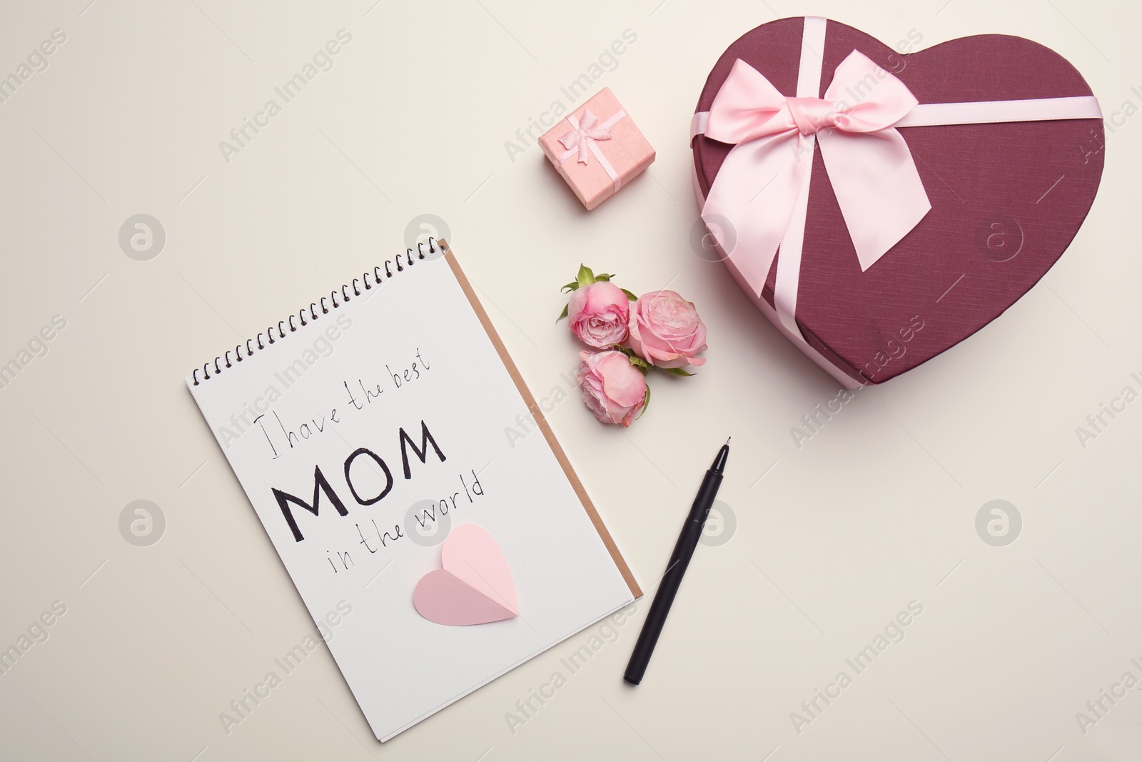 Photo of Flat lay composition with notebook, flowers and gifts for Mother's day on light background