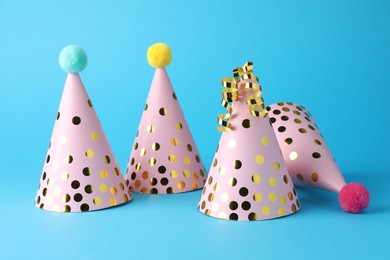 Photo of Pink party hats and serpentine streamers on light blue background