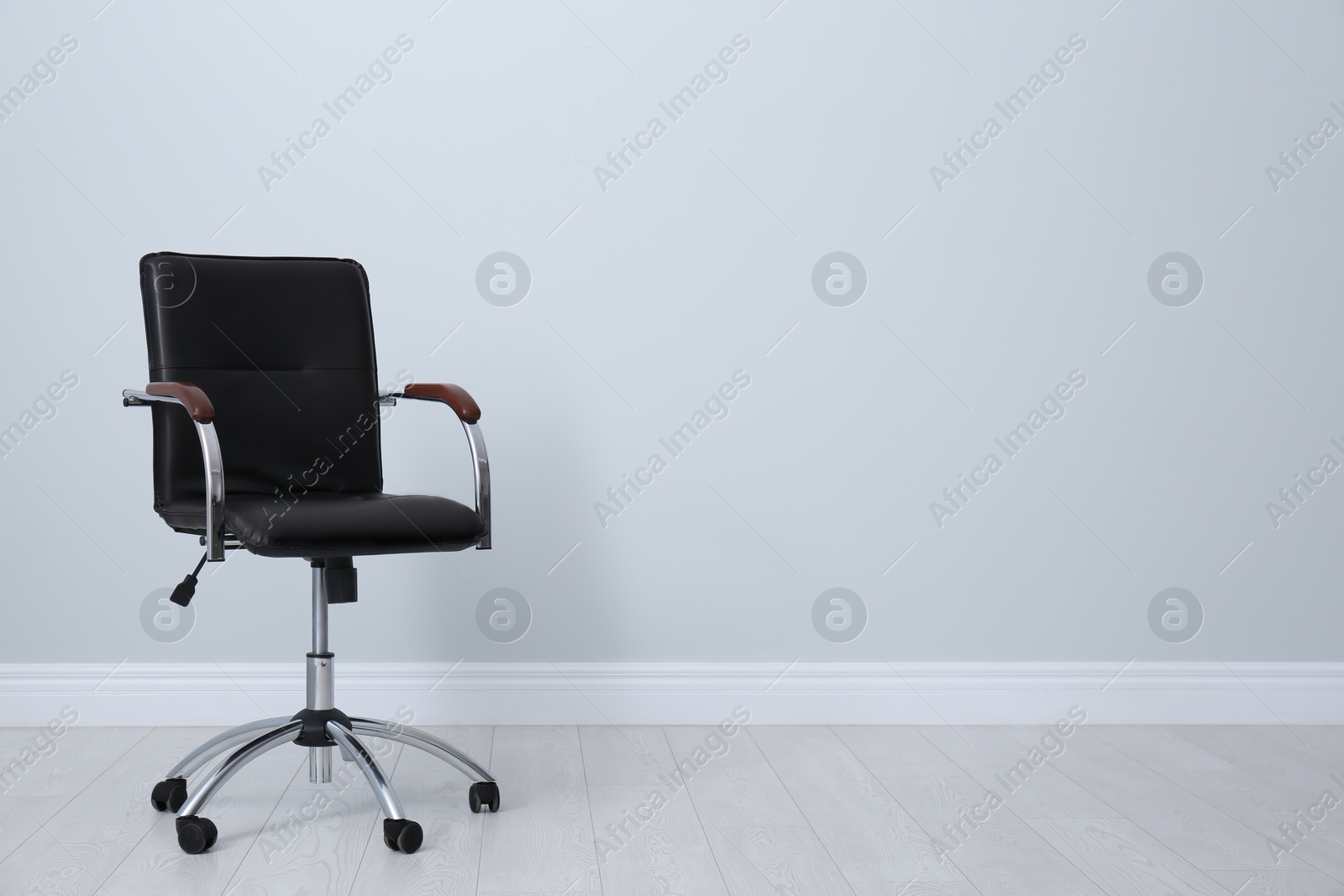 Photo of Comfortable office chair near light wall indoors. Space for text