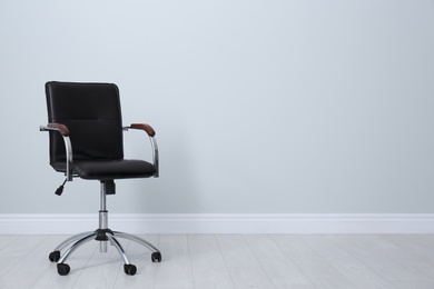 Comfortable office chair near light wall indoors. Space for text