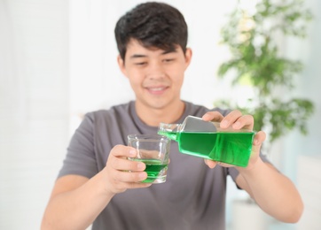 Man pouring mouthwash from bottle into glass. Teeth care