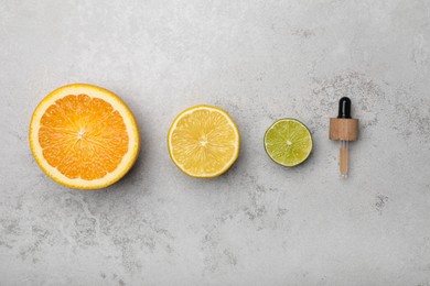 Pipette with citrus essential oil and fresh fruits on light table, flat lay