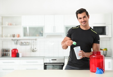 Young athletic man preparing protein shake in kitchen, space for text