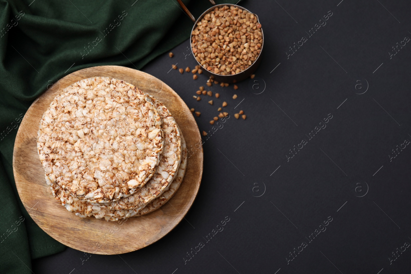 Photo of Crunchy buckwheat cakes and cereal on black table, flat lay. Space for text
