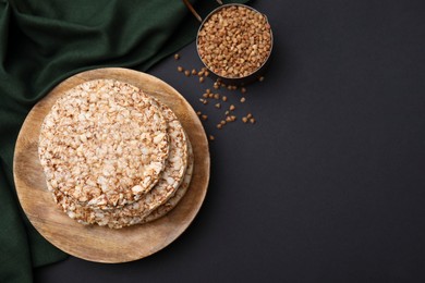 Photo of Crunchy buckwheat cakes and cereal on black table, flat lay. Space for text