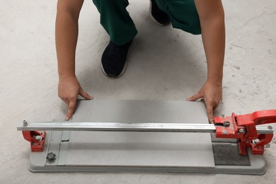 Worker using manual tile cutter on floor, closeup