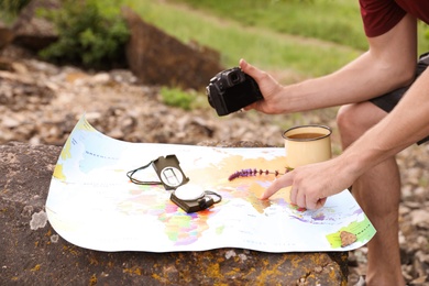 Man with camera exploring map in wilderness. Camping season