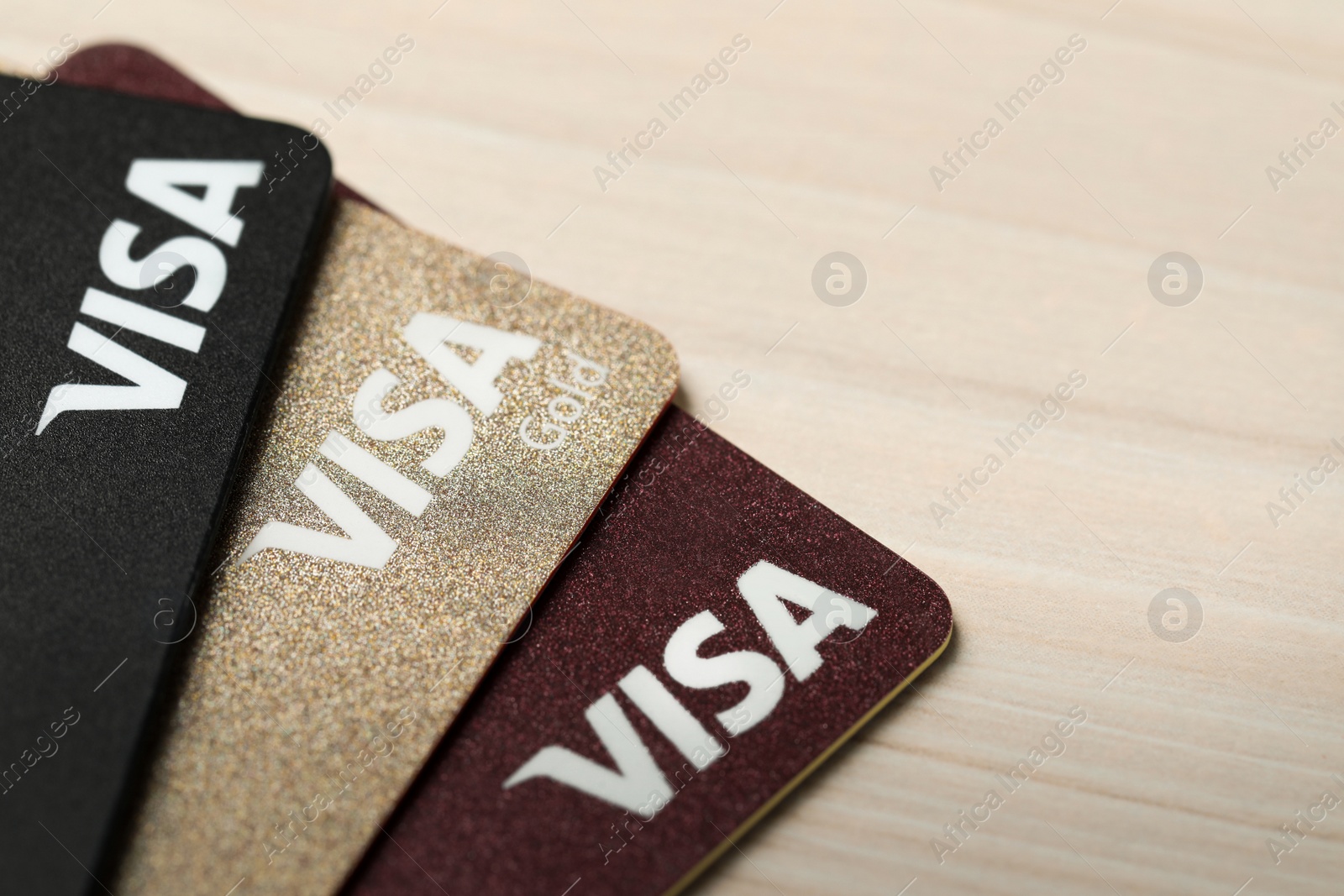 Photo of MYKOLAIV, UKRAINE - FEBRUARY 23, 2022: Bank cards of Visa payment system on wooden table, closeup