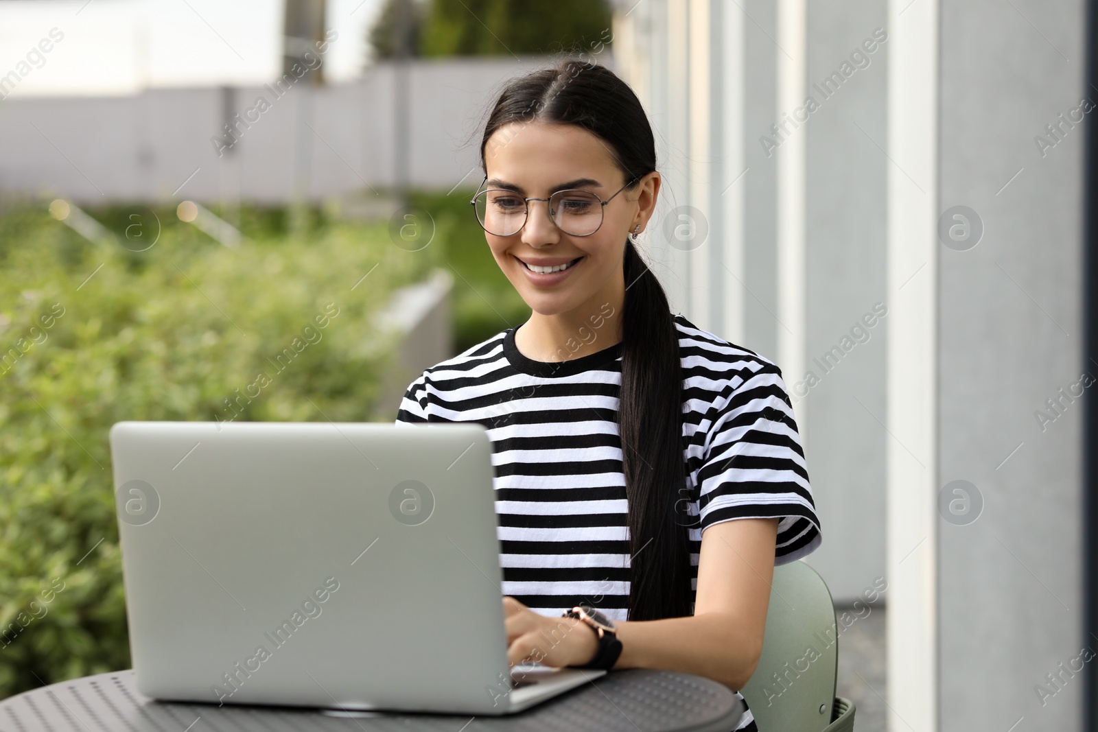 Photo of Happy young woman using modern laptop outdoors