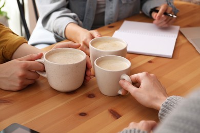 Women with cups of coffee at table in cafe, closeup