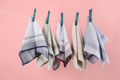 Photo of Many different handkerchiefs hanging on rope against pink background