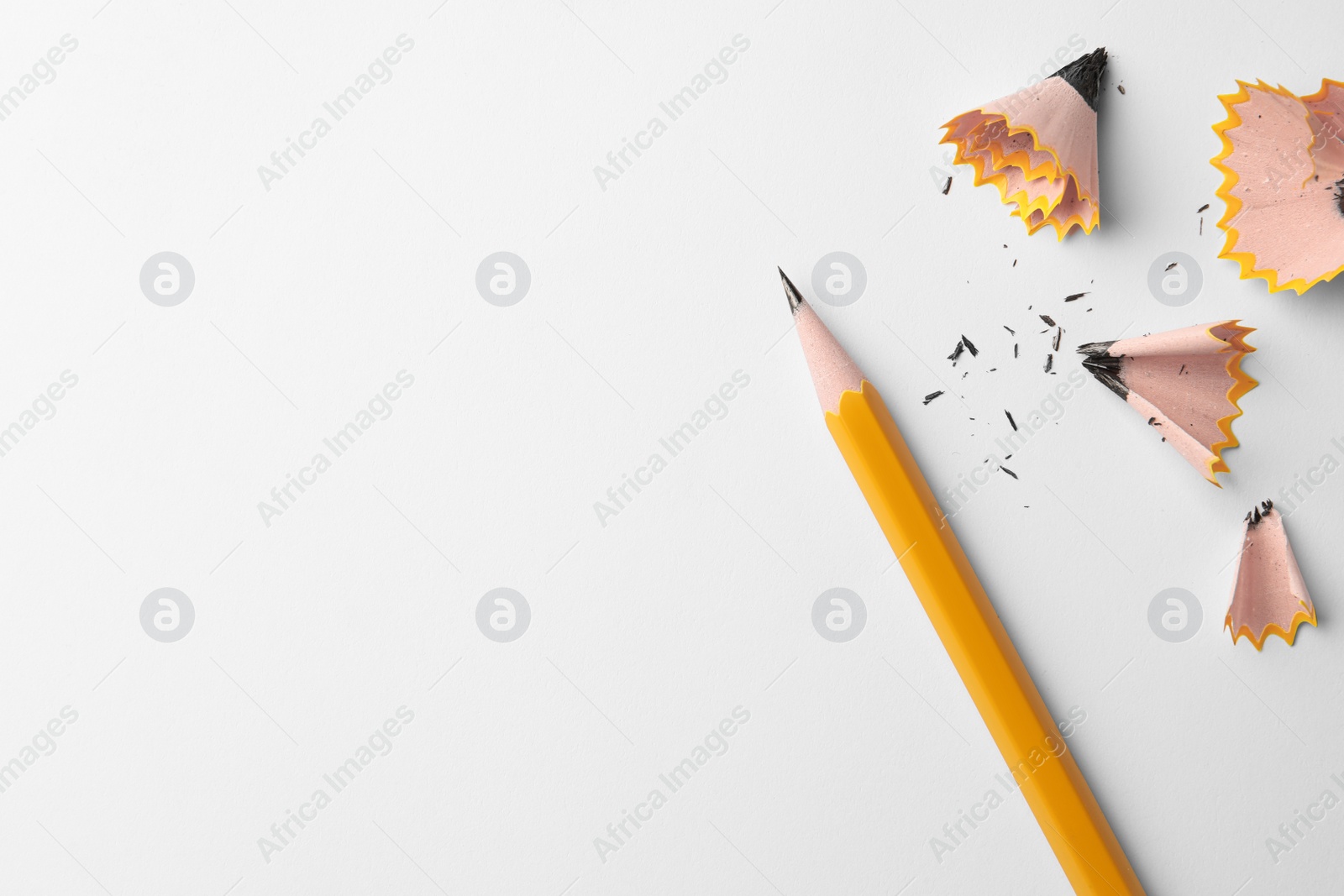 Photo of Graphite pencil and shavings on white background, flat lay. Space for text