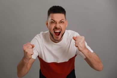 Photo of Angry man yelling on grey background. Hate concept