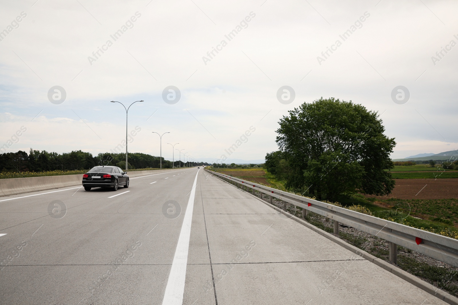 Photo of Picturesque view of asphalt road with car on cloudy day