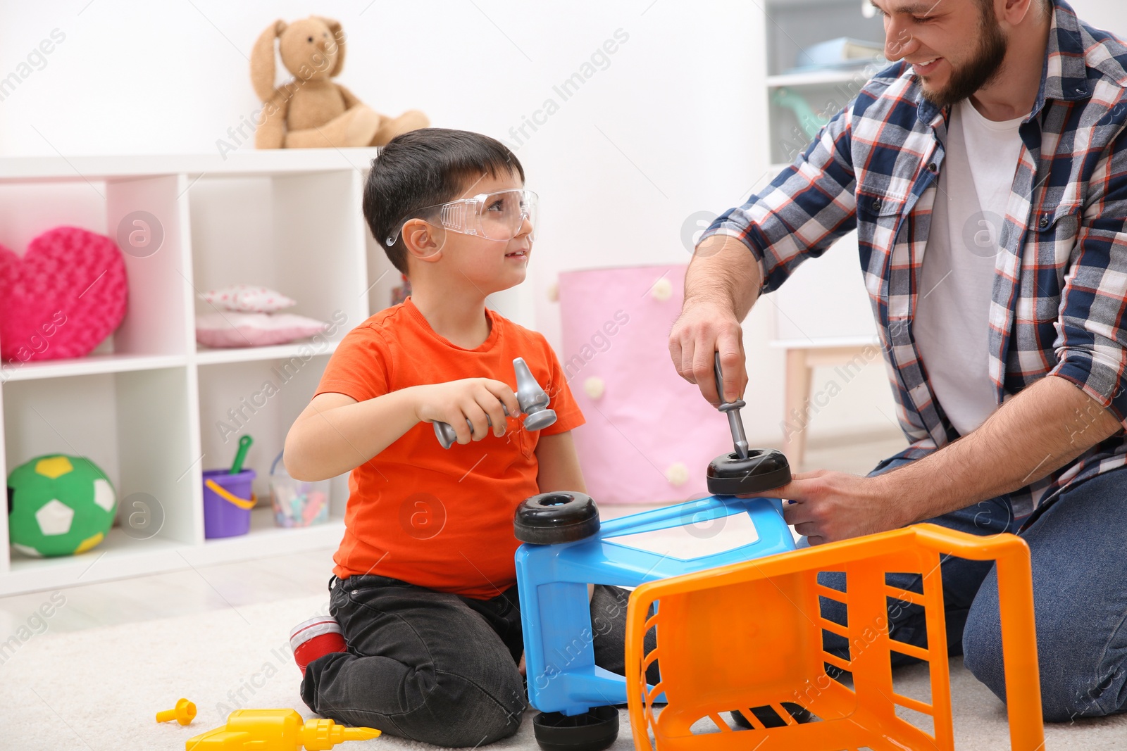 Photo of Man and his child as repairman playing with toy cart at home