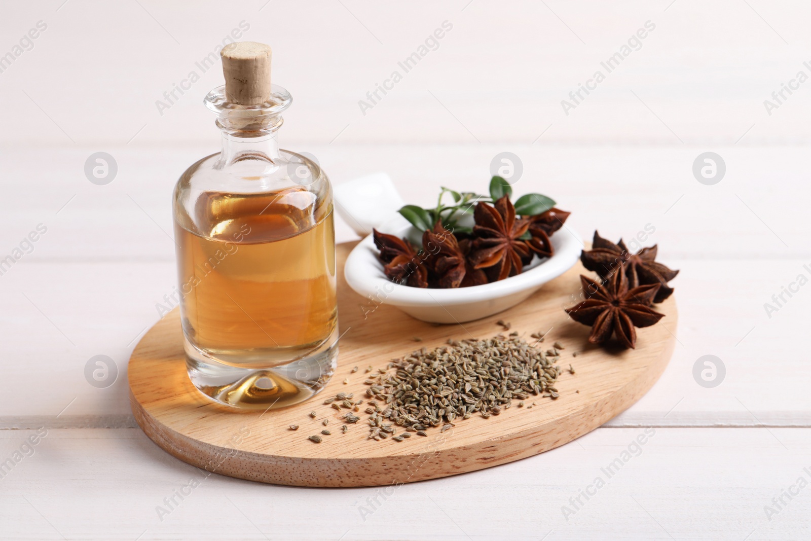 Photo of Anise essential oil and spice on white wooden table