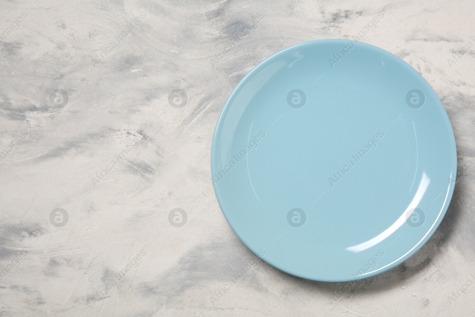 Photo of One ceramic plate on light textured table, top view. Space for text