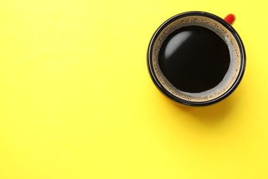 Photo of Aromatic coffee in cup on yellow background, top view. Space for text