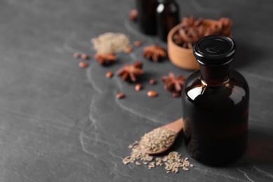 Photo of Bottle of anise essential oil and seeds on black table. Space for text