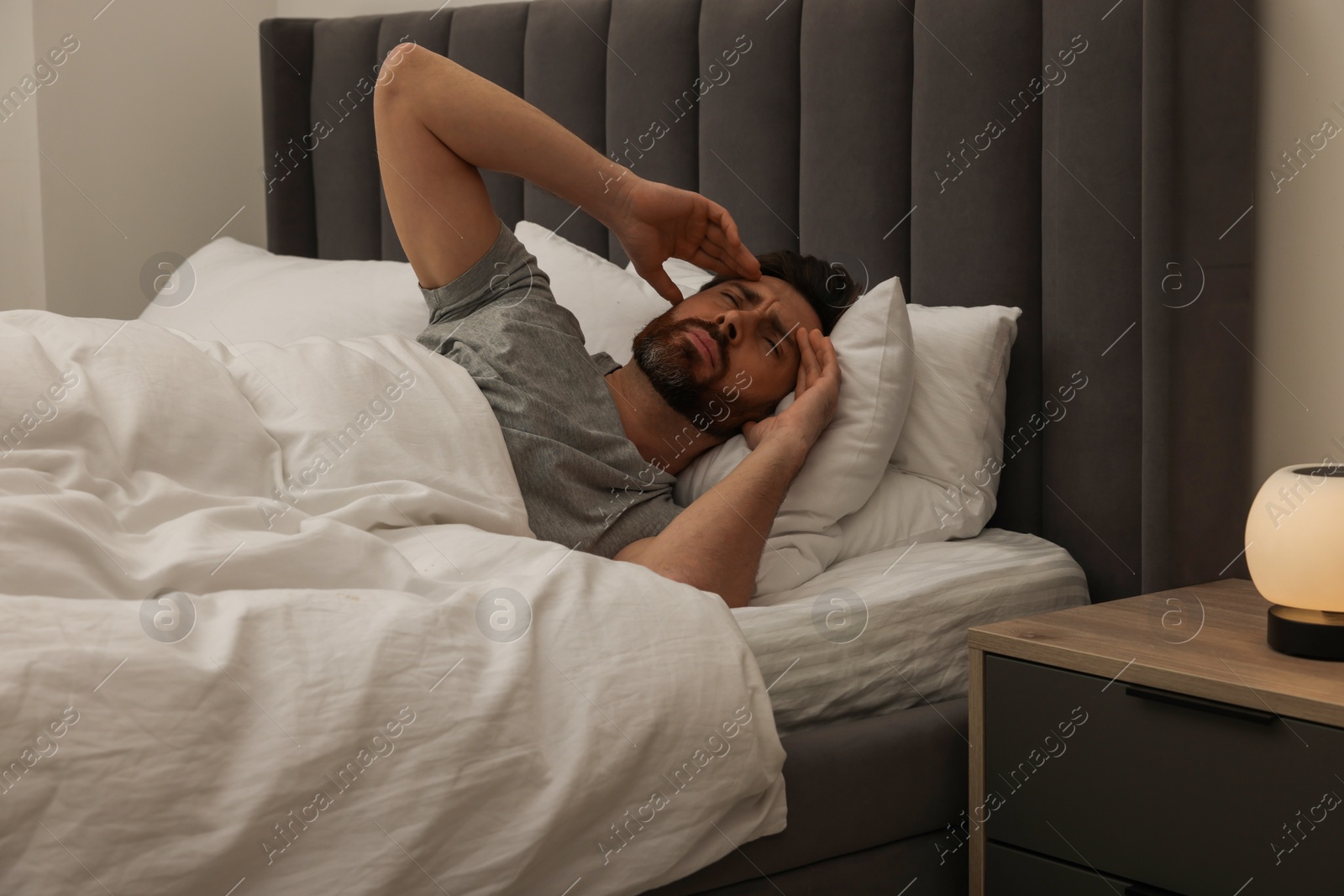 Photo of Man suffering from headache in bed at night