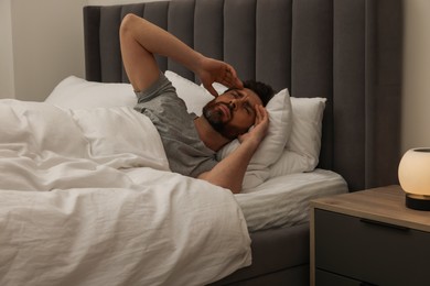 Man suffering from headache in bed at night