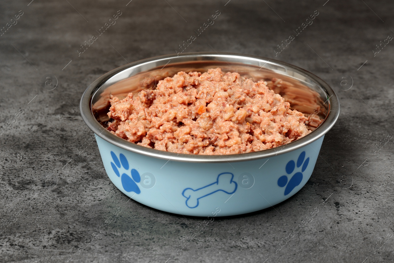 Photo of Wet pet food in feeding bowl on grey stone background