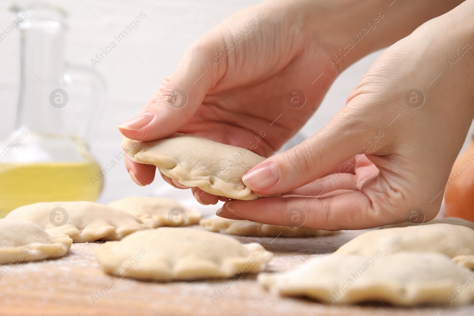 Photo of Woman making dumplings (varenyky) with tasty filling at table, closeup