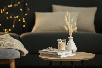 Photo of Side table with books and decor near sofa in room