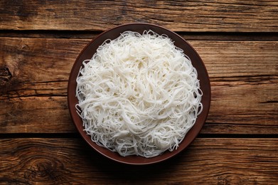 Photo of Bowl with cooked rice noodles on wooden table, top view