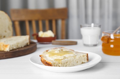 Photo of Slice of bread with butter, honey and milk on white wooden table