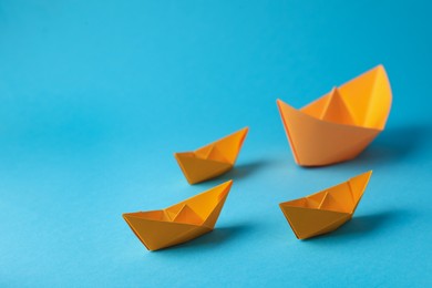 Photo of Handmade orange paper boats on light blue background. Space for text