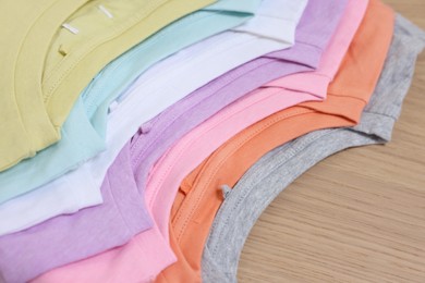 Photo of Many stacked clothes on wooden table, closeup