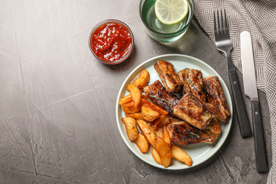 Photo of Delicious grilled ribs served on grey table, flat lay. Space for text