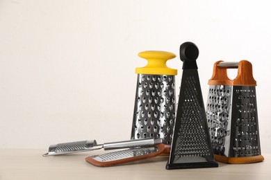 Photo of Different modern graters on white wooden table. Space for text