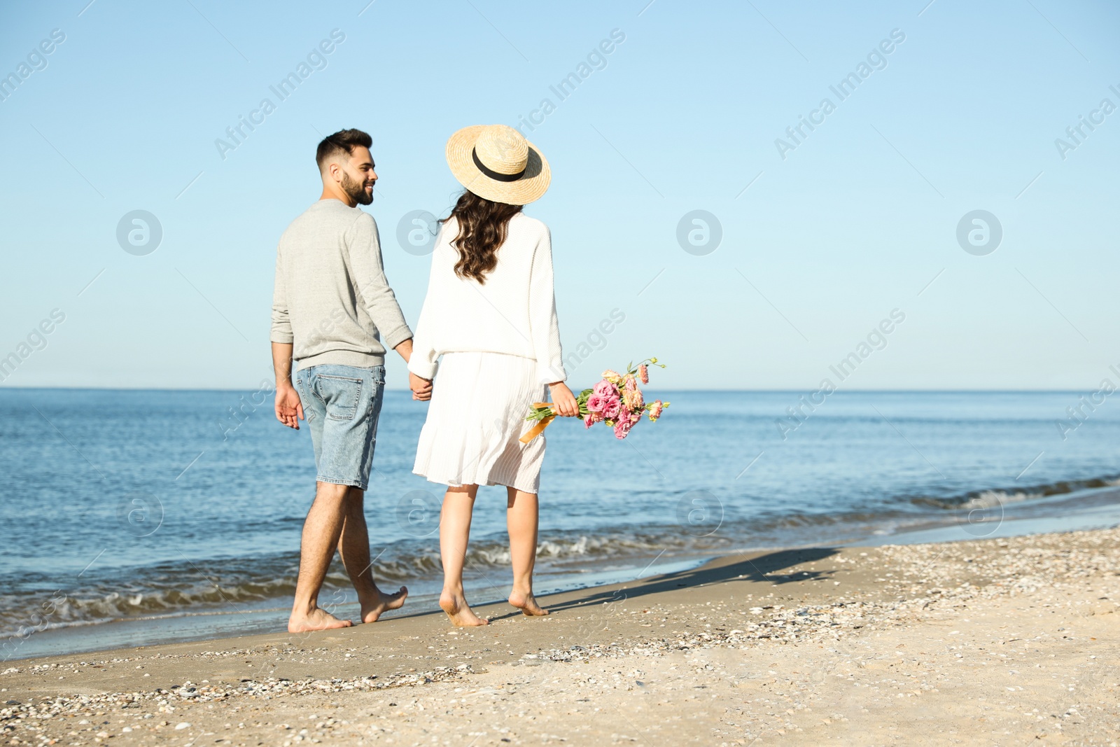 Photo of Happy young couple walking on beach near sea. Honeymoon trip