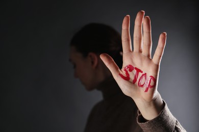 Photo of Woman with word Stop written on hand against black background, closeup and space for text. Domestic violence concept