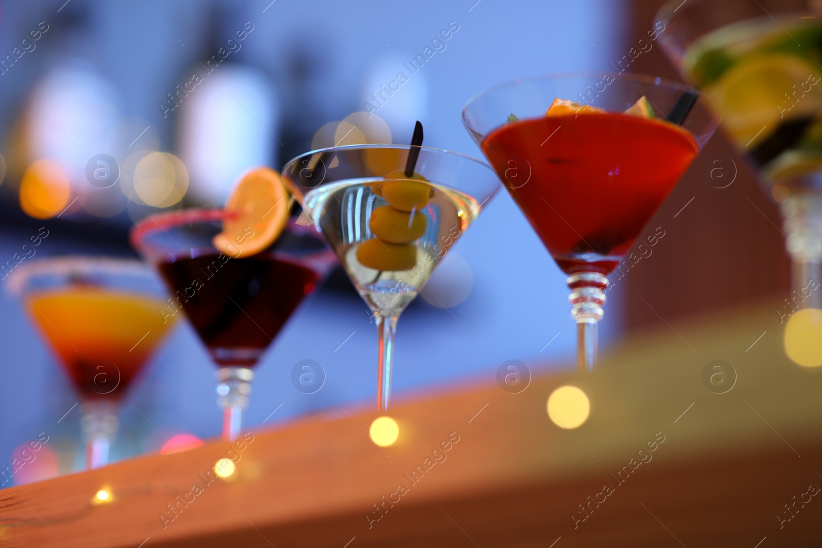 Photo of Different martini cocktails on table in bar, closeup