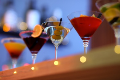 Photo of Different martini cocktails on table in bar, closeup