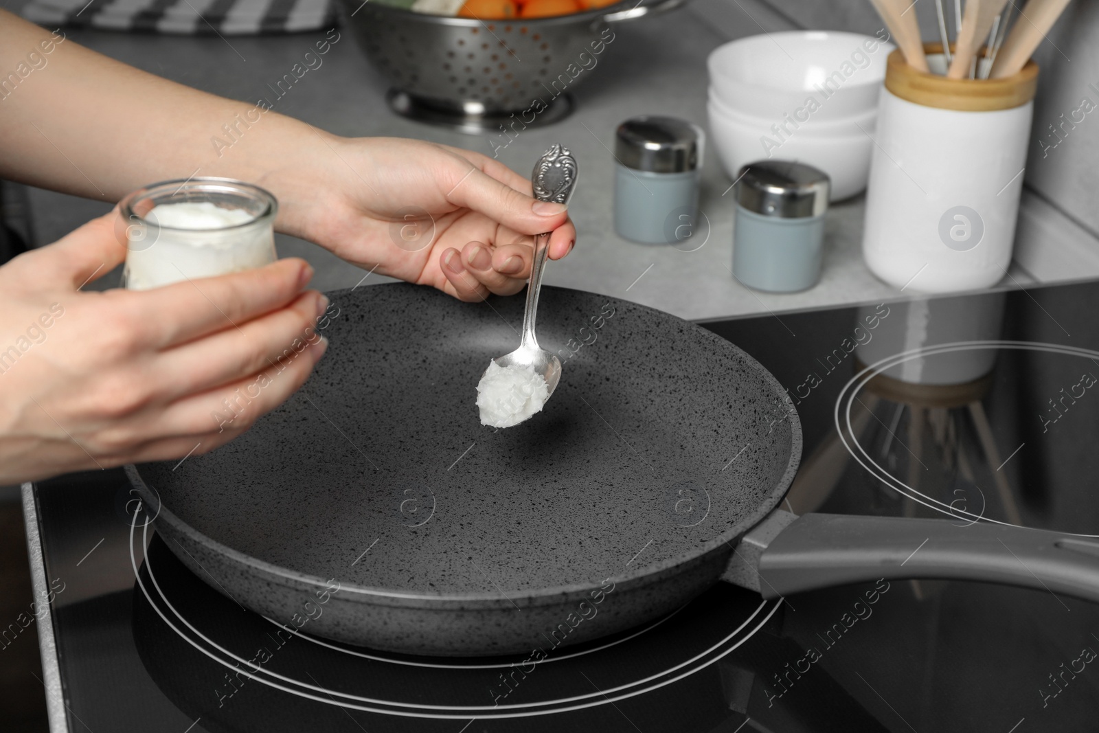 Photo of Woman cooking with coconut oil on induction stove, closeup