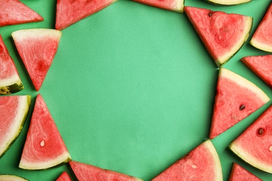 Frame made with slices of ripe watermelon on green background, flat lay. Space for text