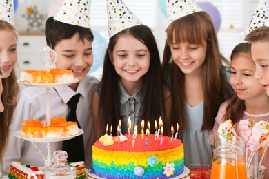 Photo of Happy children near cake with candles at birthday party indoors