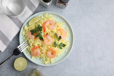 Photo of Delicious risotto with shrimps, lime and parsley served on light grey table, flat lay. Space for text