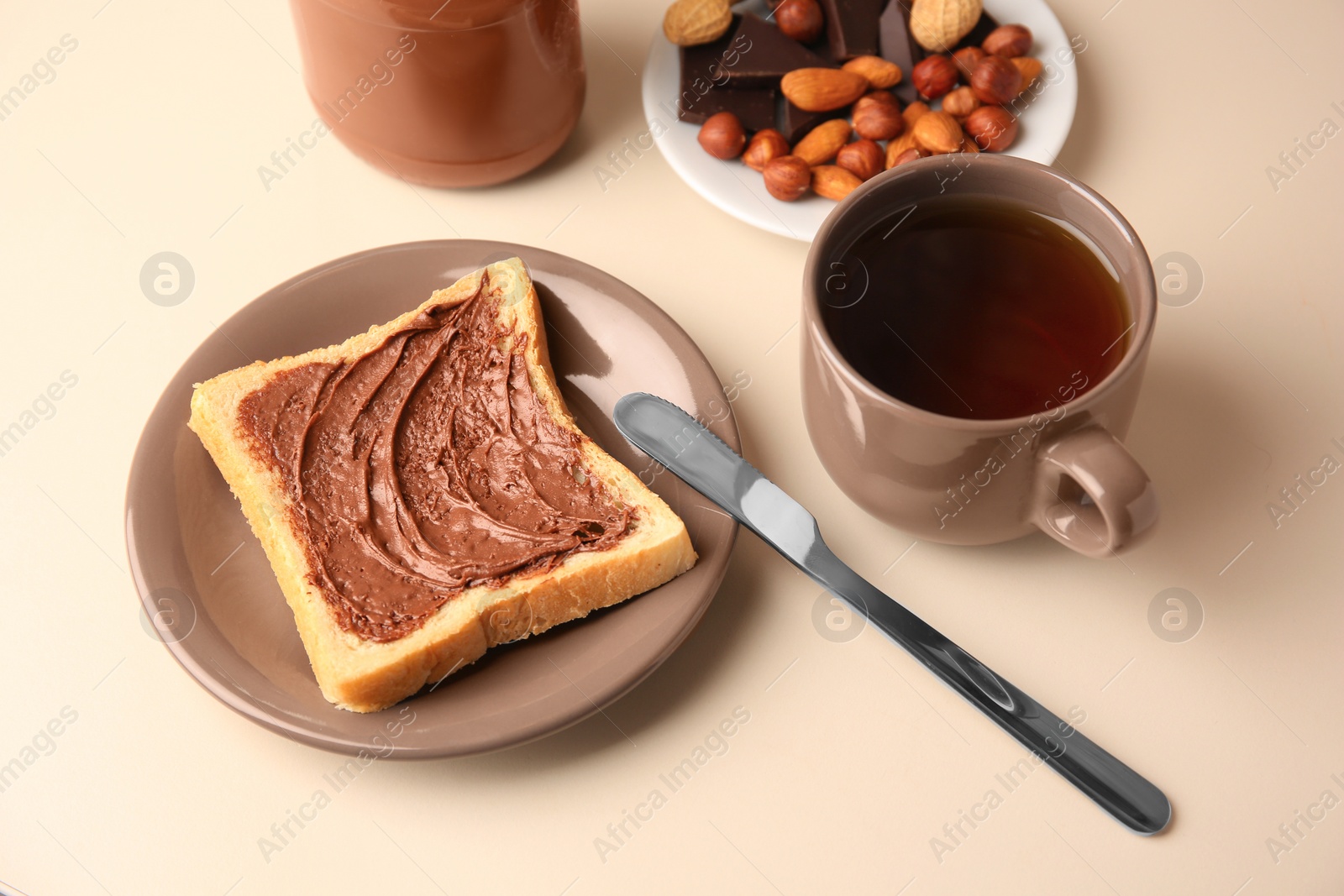 Photo of Tasty toast with chocolate paste and cup of tea served on light table