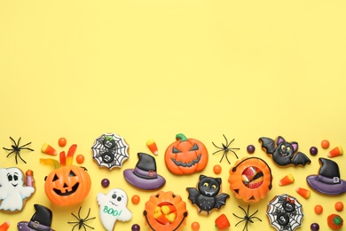 Photo of Tasty cookies and sweets for Halloween party on yellow background, flat lay. Space for text