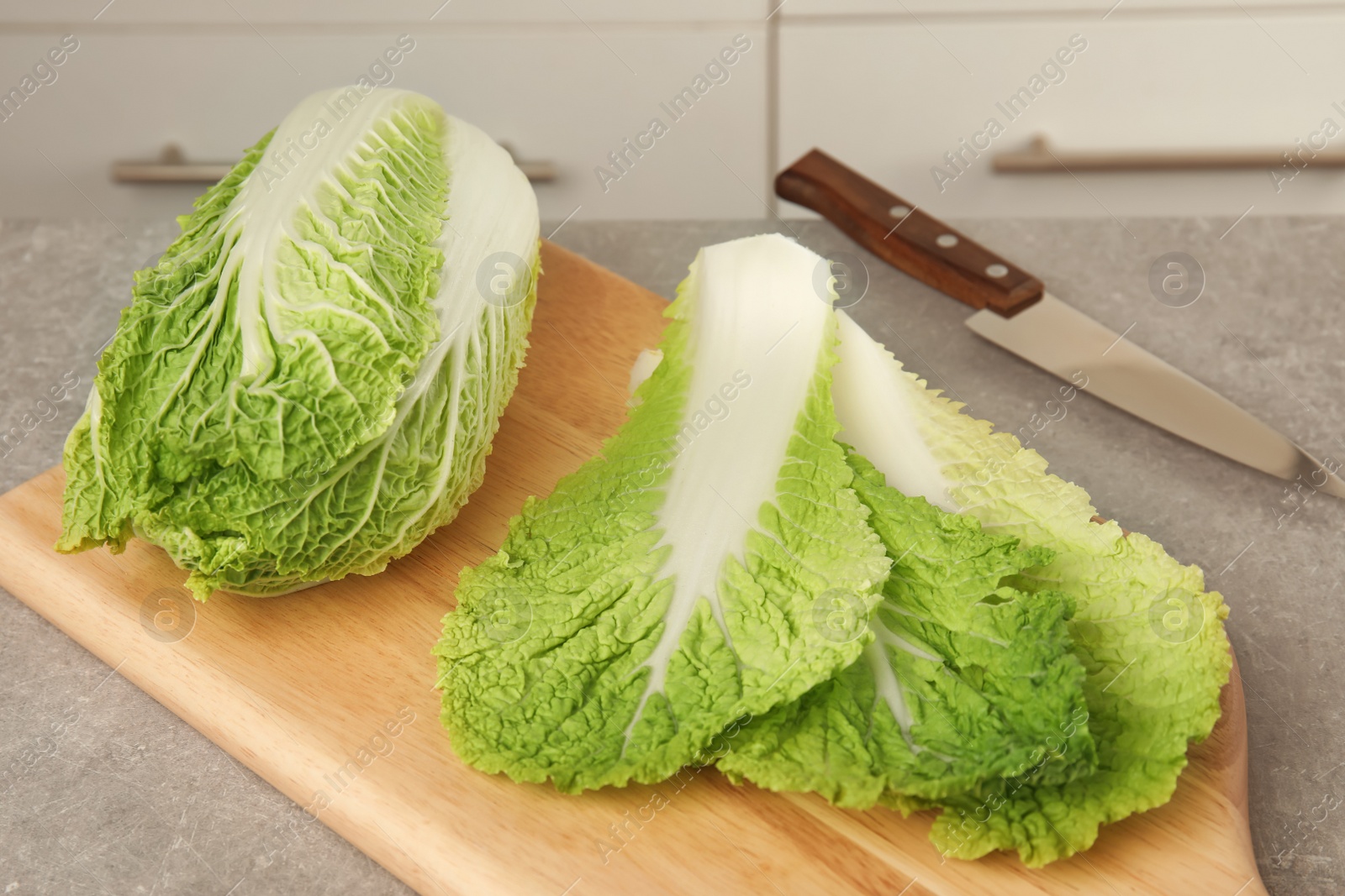 Photo of Wooden board with fresh ripe cabbage on table. Healthy food