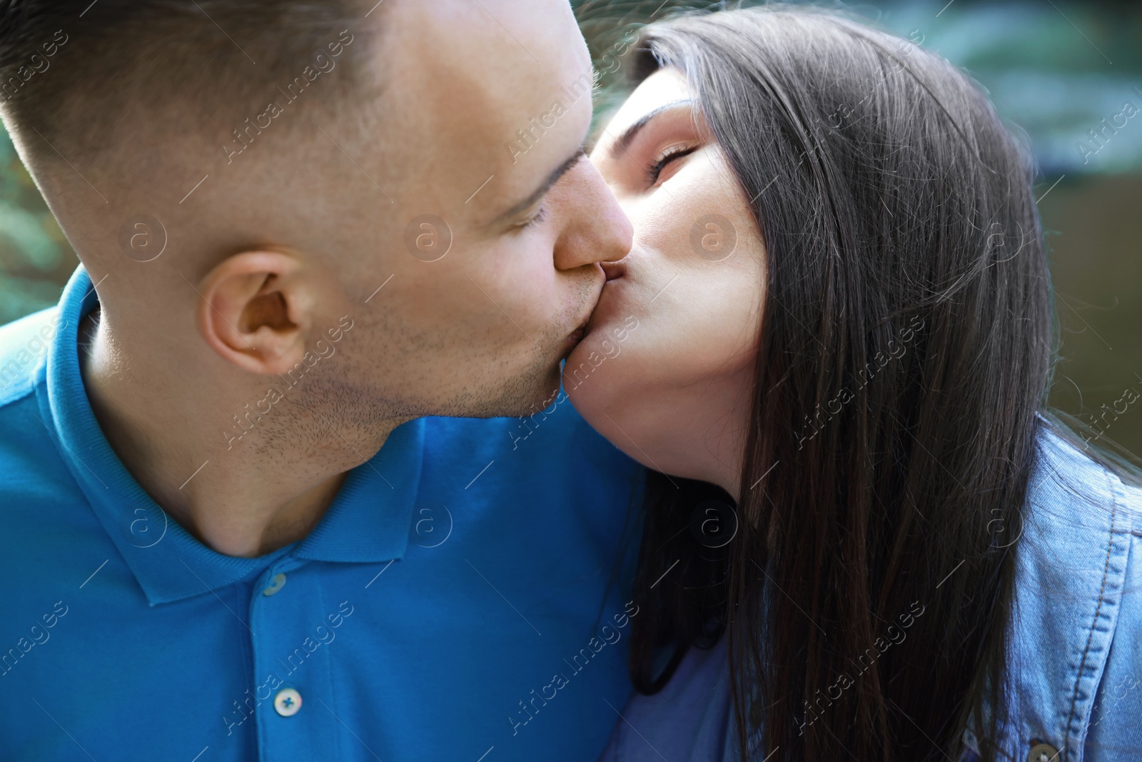 Photo of Affectionate young couple kissing outdoors, closeup view