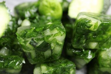 Photo of Ice cubes with cucumber slices and herbs, closeup