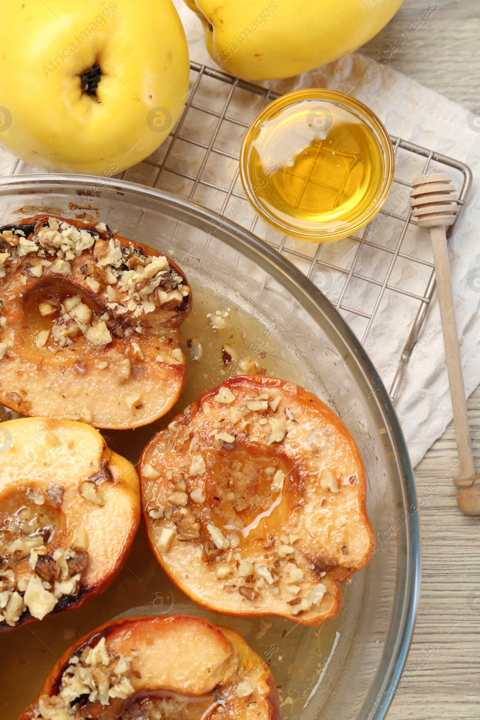 Photo of Delicious baked quinces with nuts in bowl, honey and fresh fruits on wooden table, flat lay