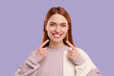 Photo of Beautiful woman showing her clean teeth and smiling on violet background